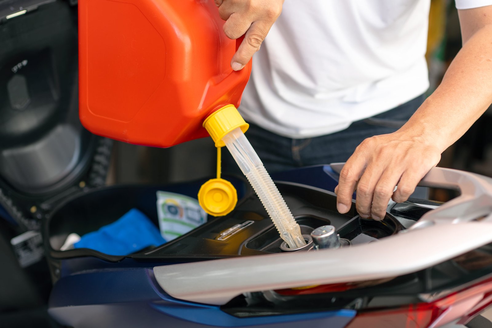 Mechanic filling up fuel  into the Motorcycle tank with gasoline